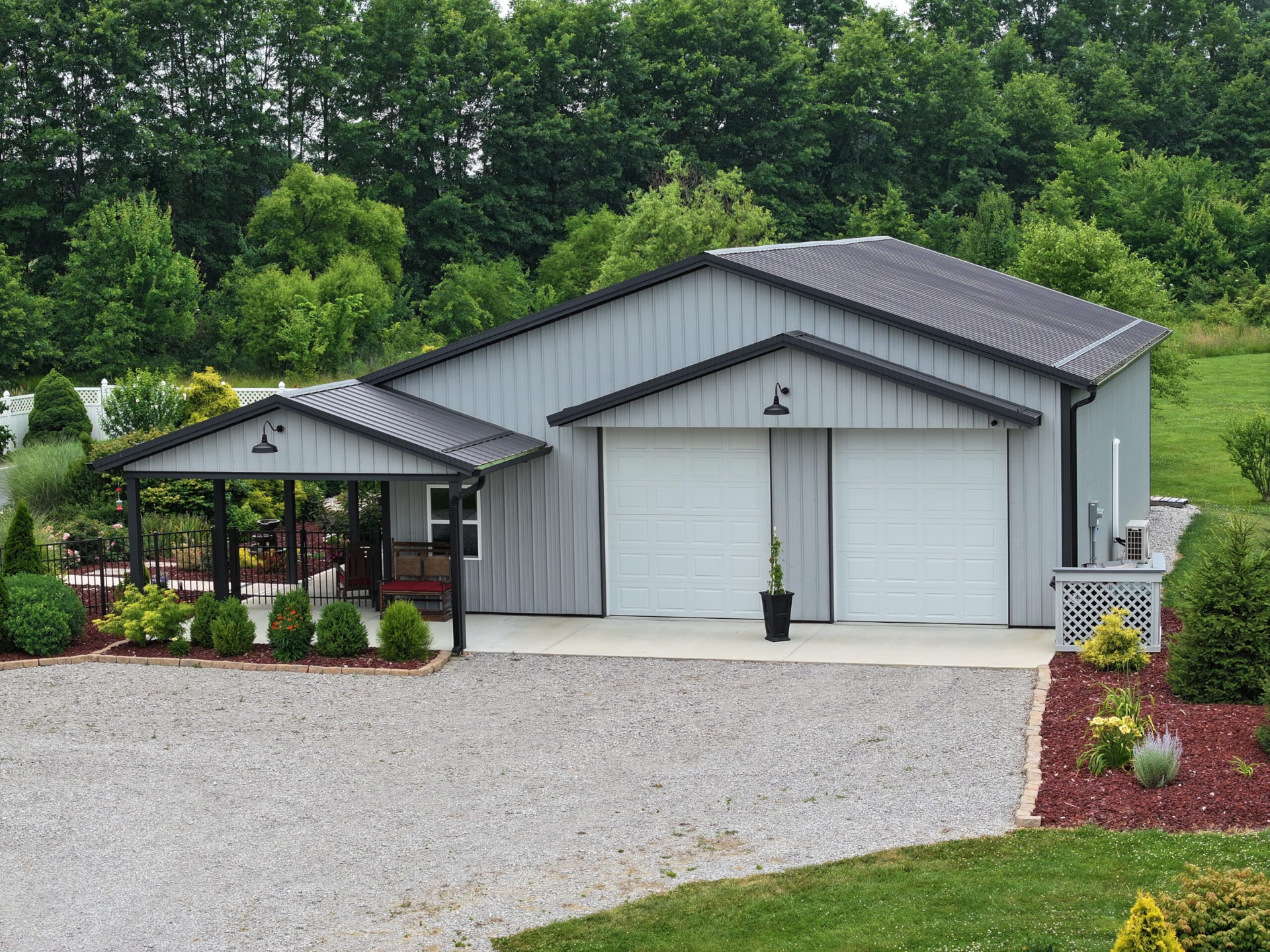 Gray post frame garage with two overhead doors and a landscaped pavilion built in Southern Ohio