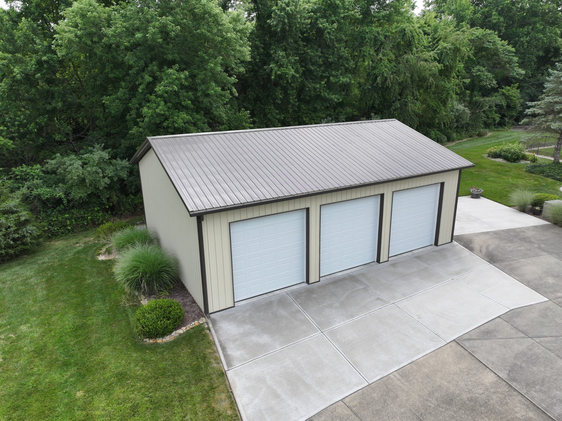 Cream three car post frame garage with bronze metal roof and concrete driveway in Southern Ohio