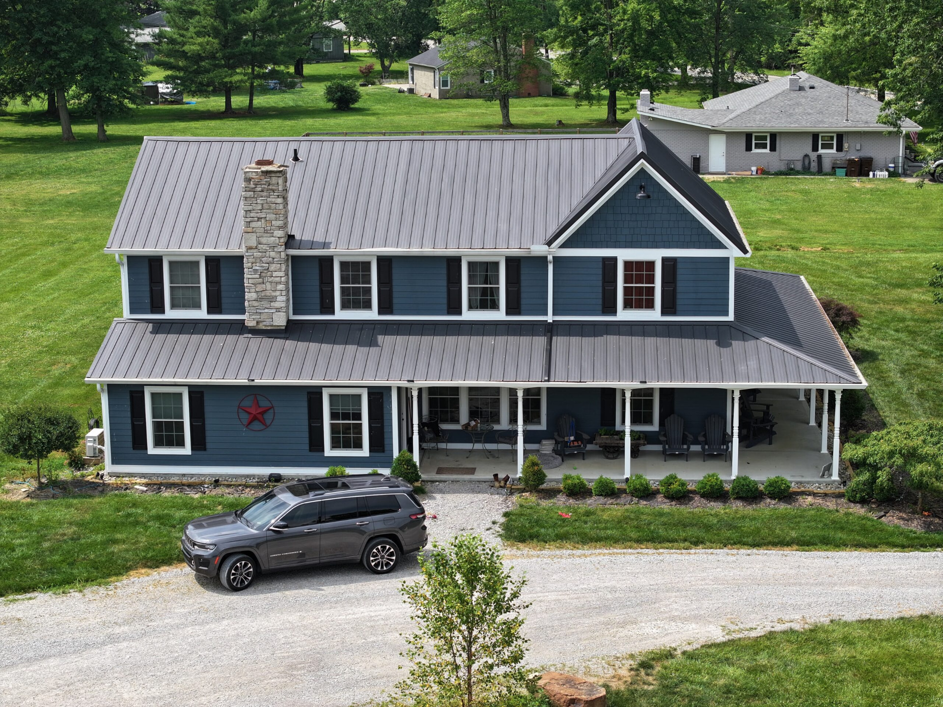 Blue two story farmhouse with a new standing seam metal roof and full front porch in Southern Ohio