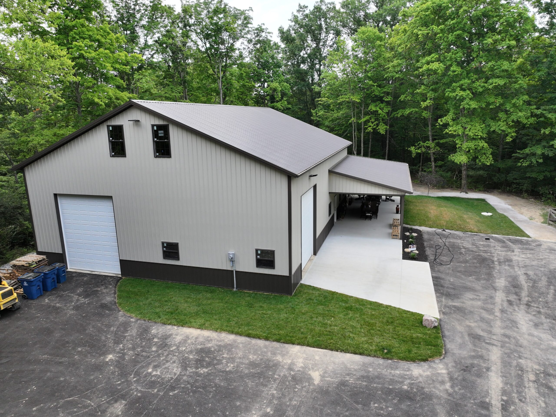 Tall post frame workshop with tan siding, brown wainscot, and covered breezeway in Southern Ohio